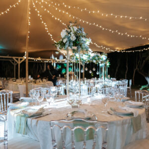 Photo d'un mariage à La Réunion – Centre de table en hauteur – Décoration florale, Chaises napoléon transparentes, Guirlandes lumineuses