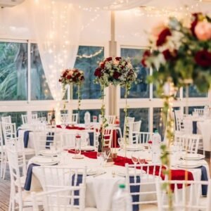 Photo d'un mariage à La Réunion – Centre de table en hauteur – Chaises chiavari blanches, Guirlandes lumineuses, Tentures pour plafond