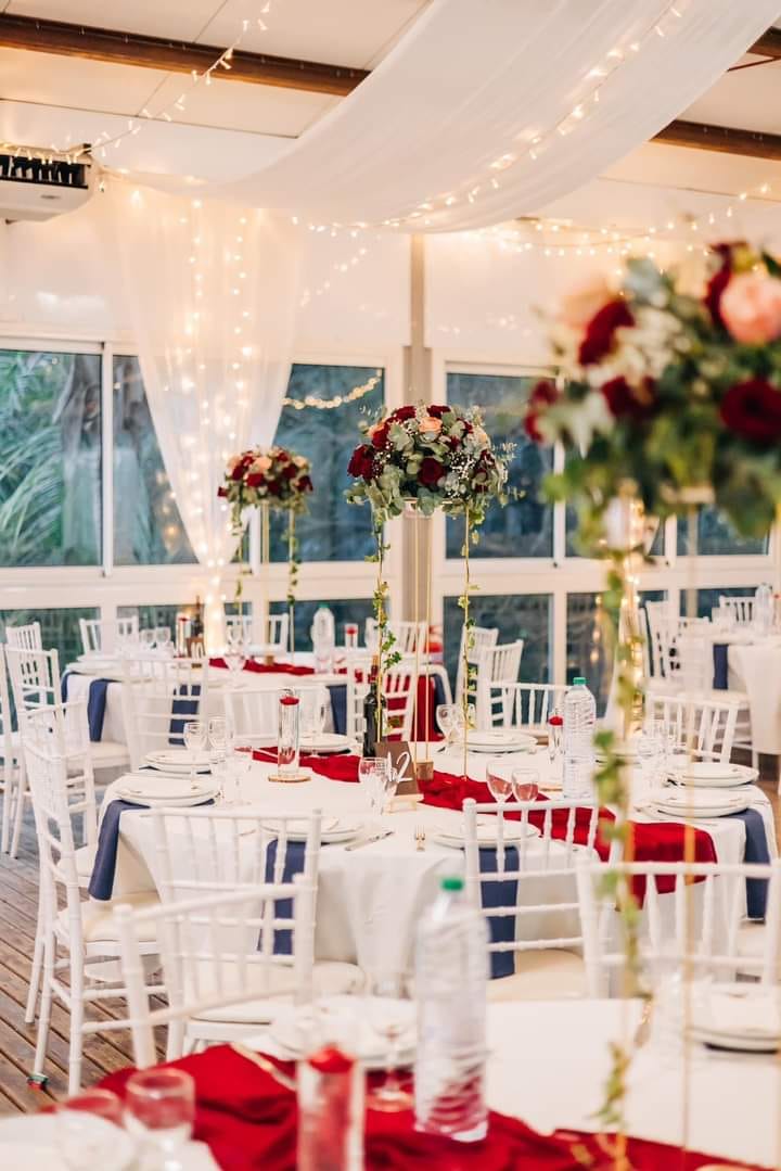 Photo d'un mariage à La Réunion – Centre de table en hauteur – Chaises chiavari blanches, Guirlandes lumineuses, Tentures pour plafond
