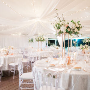 Photo d'un mariage à La Réunion – Centre de table en hauteur – Chaises napoléon transparentes, Tentures murales, Guirlandes lumineuses