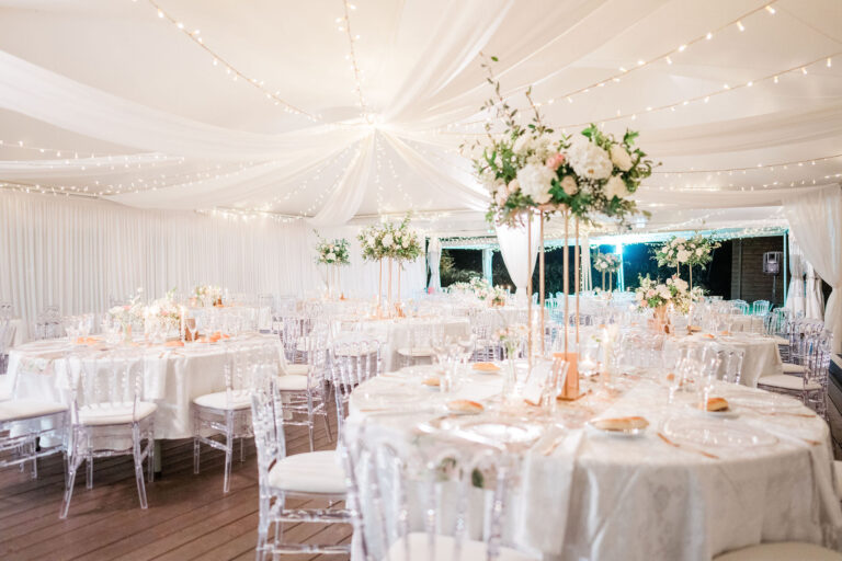 Photo d'un mariage à La Réunion – Centre de table en hauteur – Chaises napoléon transparentes, Tentures murales, Guirlandes lumineuses